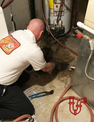 Plumber working on clogged drain in basement
