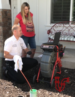 Plumber outside with customer checking pipe with drain camera